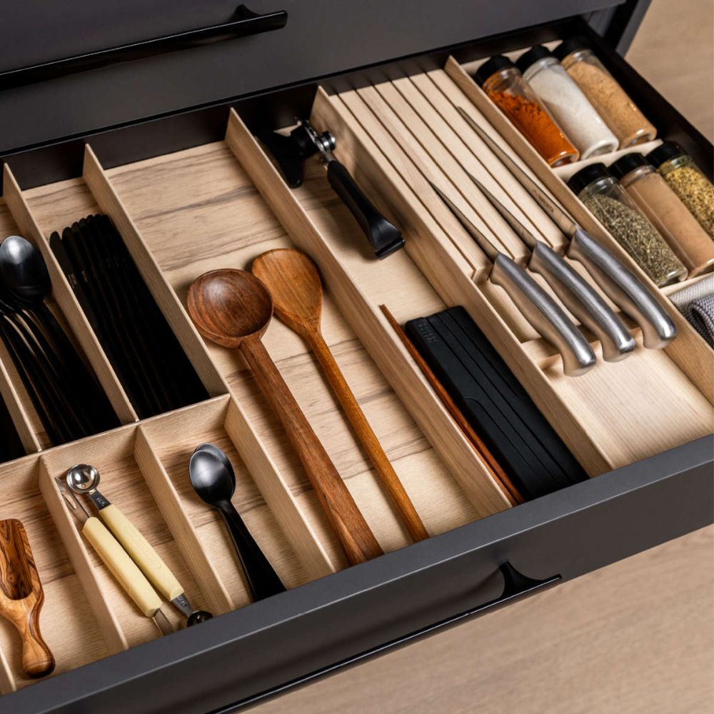 Eine organisierte Küchenschublade mit hölzernen Trennwänden sorgt für perfekte Ordnung; Utensilien und Gewürzdosen sind übersichtlich angeordnet, und der FineLine LiniQ Messerblock sorgt für die sichere Aufbewahrung von Messern in der Schublade.