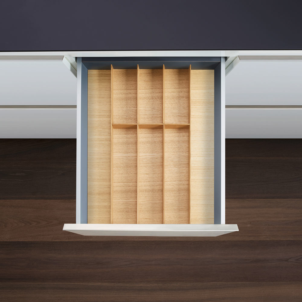 Eine offene Küchenschublade von oben zeigt einen leeren FineLine LiniQ Besteckeinsatz - Besteckkasten mit mehreren Fächern in einer dunklen Holzarbeitsplatte - ideal für die stilvolle Küchenorganisation.