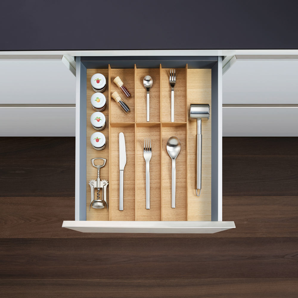 Eine offene Küchenschublade mit FineLine LiniQ Besteckeinsatz - Besteckkasten aus Eschenholz, in dem Besteck, Korkenzieher, Fleischklopfer, Gewürzgläser und andere Utensilien perfekt organisiert sind.