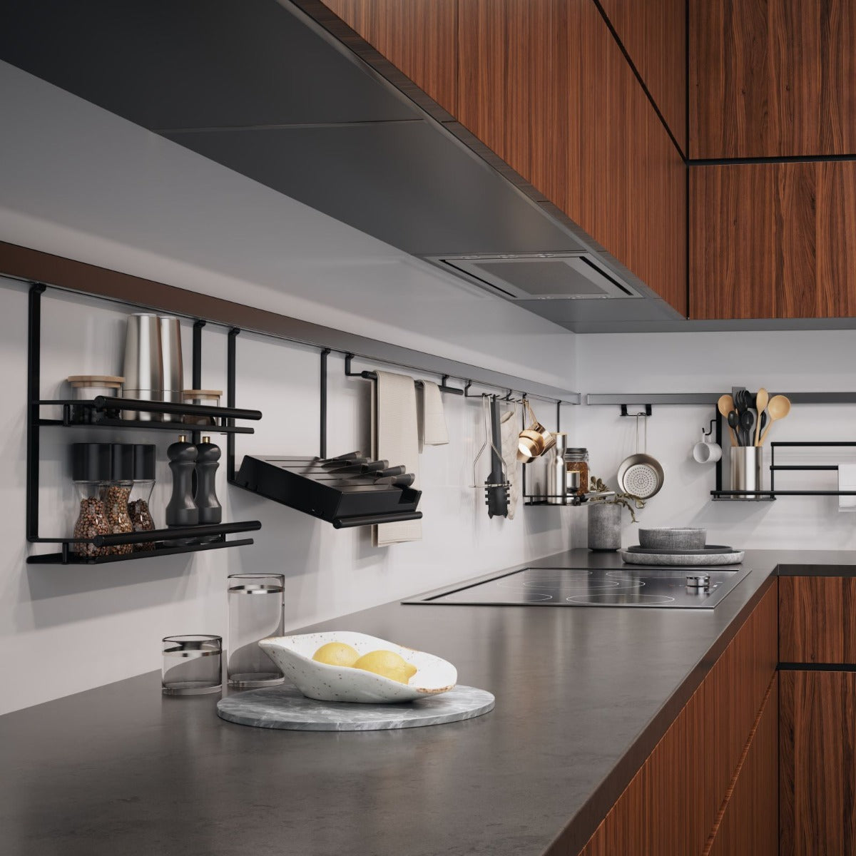 Moderne Küche mit Holzschränken, grauer Arbeitsplatte und Utensilien, die ordentlich auf schwarzen Wandregalen im Stil von Kesseböhmer Linero schwarz (Aluprofil Edelstahloptik 600-1800 mm) angeordnet sind. Eine weiße Schale mit Zitronen auf einem Marmortablett unterstreicht die smarte Küchenorganisation.