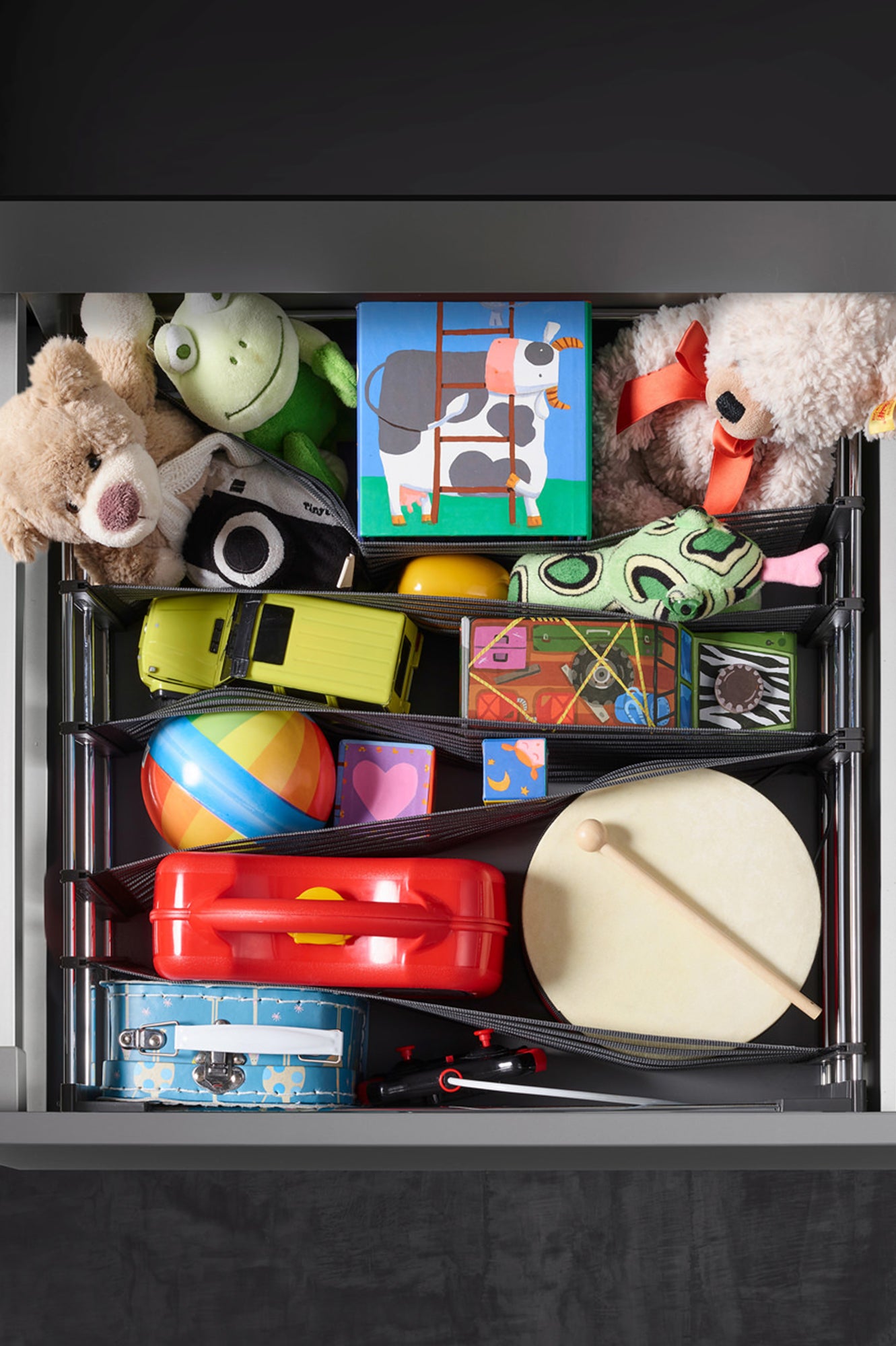 Offene Schublade von oben mit Schubladenorganizer, in dem bunte Spielsachen verstaut sind.
