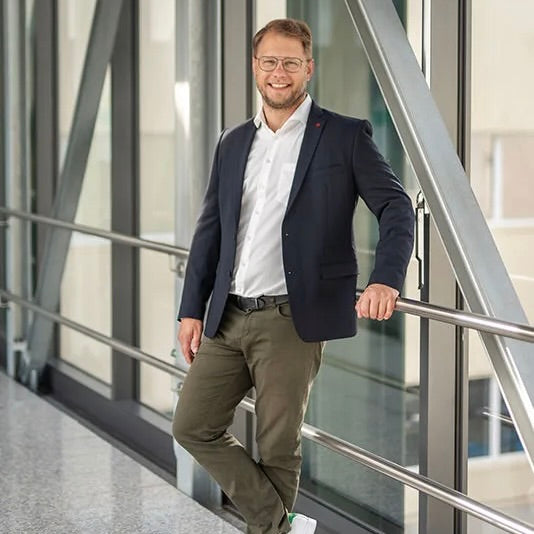 Blonde männliche Person mit Brille und Jacket auf Skywalk