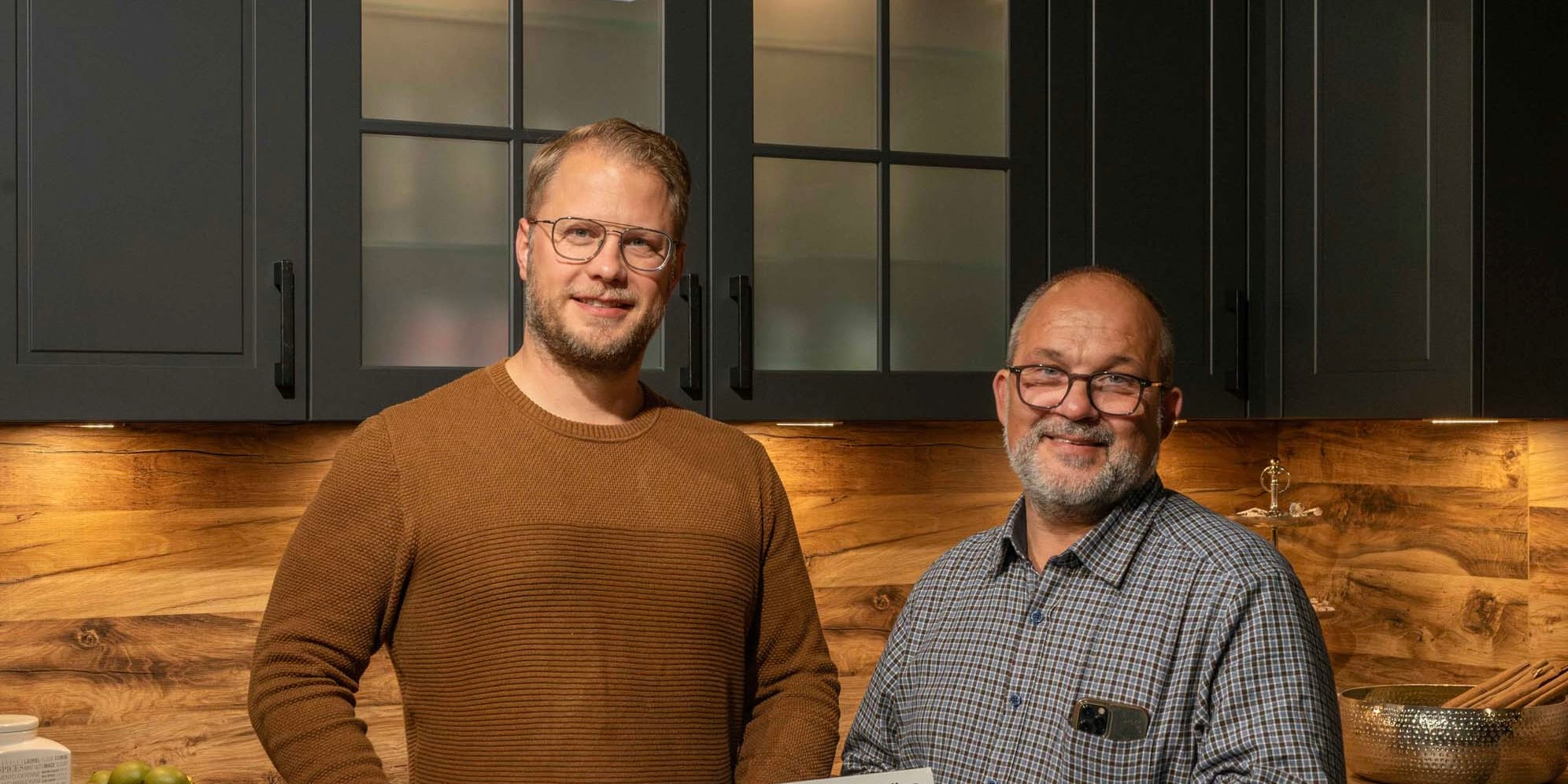 Zwei männliche Personen in dunkler Küche