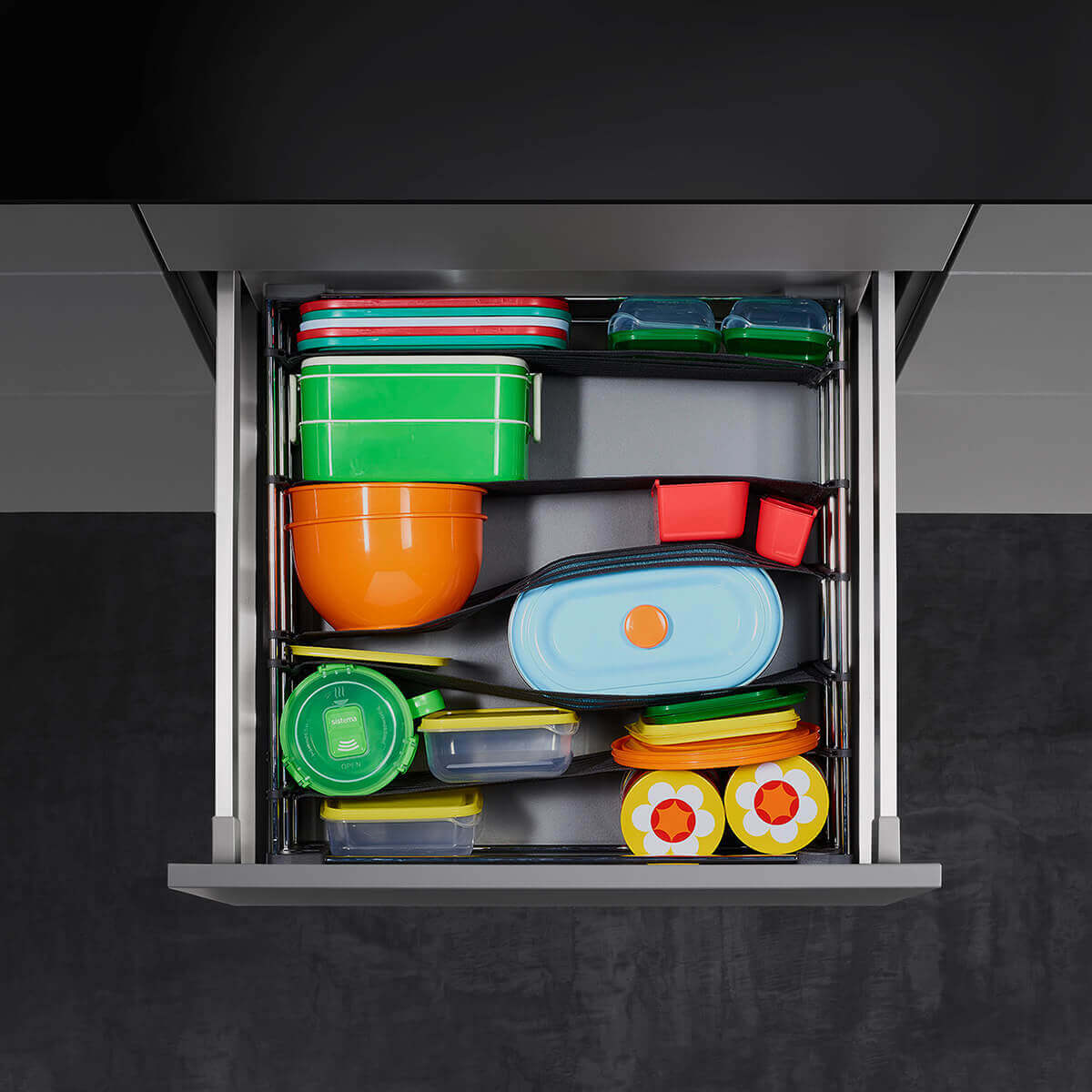 Offene Schublade von oben mit Schubladenorganizer, in dem bunte Dosen und Deckel verstaut sind
