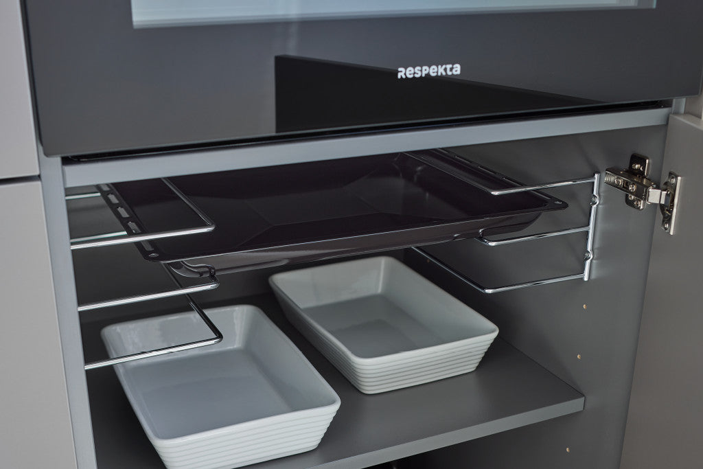 Blick in einen geöffneten Unterschrank: Ein Backblech liegt auf einem Backblechhalter, darunter weiße Auflaufformen