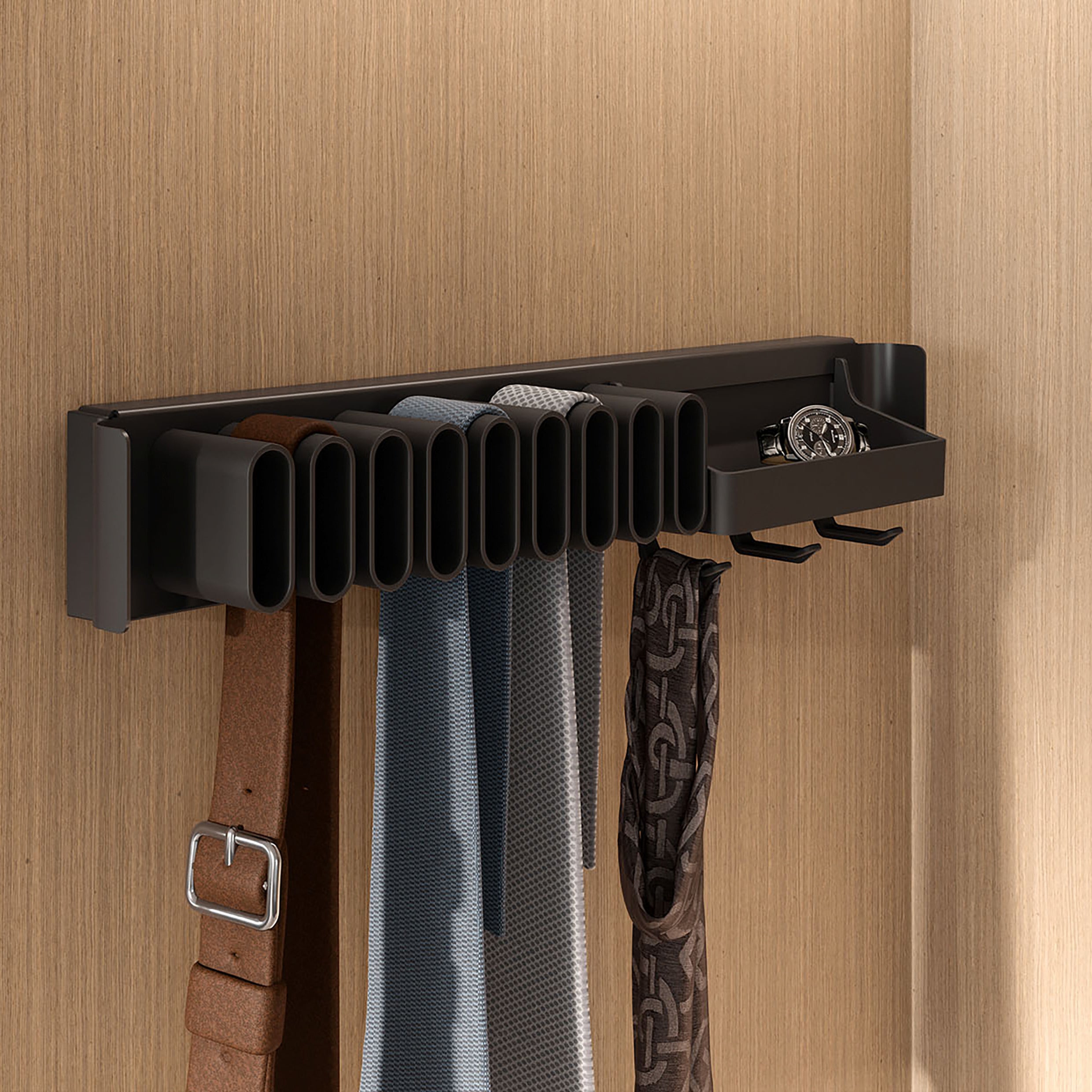 Der CONERO Gürtel- und Krawattenhalter mit Schale (Auszug) in Schwarz wird an der Wand montiert und bietet Platz für Gürtel, Krawatten, eine Uhr und kleine Accessoires. Er verfügt über mehrere vertikale Schlitze und zwei Haken für eine organisierte Aufbewahrung vor einem Holzhintergrund.