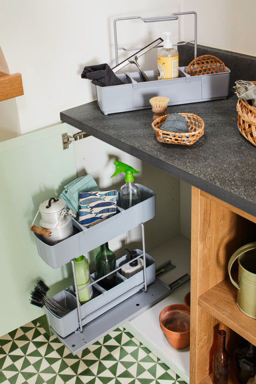 Ausgefahrener, bodenmontierter Putzmittelauszug bestückt mit Putzutensilien in Küche.