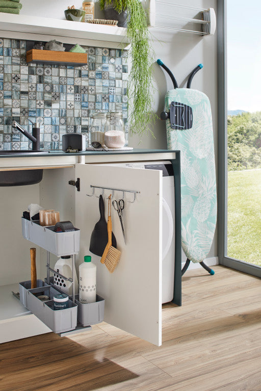 Geöffneter Unterschrank mit herausgezogenem Putzmittelauszug. Dieser enthält bunte Putzmittelflaschen und Schwämme.