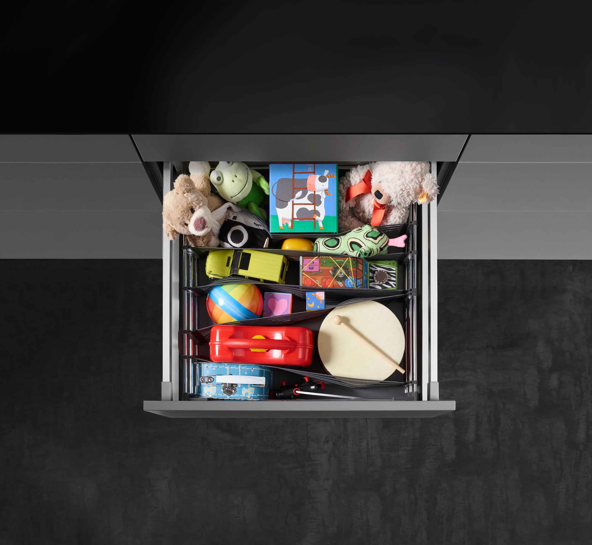 Offene Schublade von oben mit Schubladenorganizer, in dem bunte Spielsachen verstaut sind.