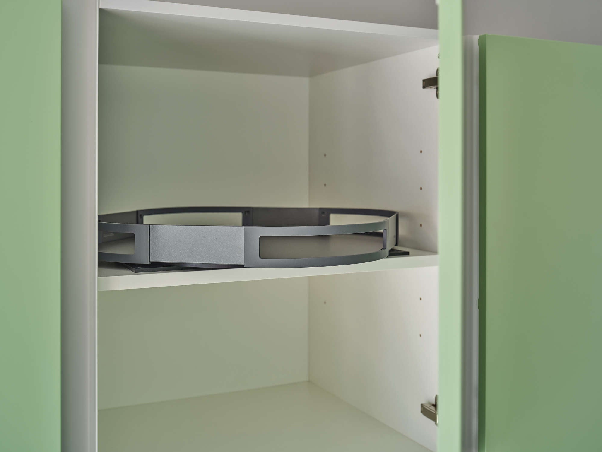Geöffneter Hängeschrank in grüner Küche mit einem auf  Zwischenboden montierten Drehtablar.