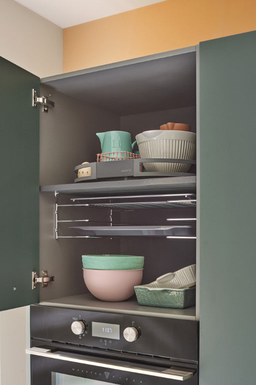 Geöffneter, dunkelgrüner Küchenschrank über Backofen mit Geschirr und Auszug für Backbleche