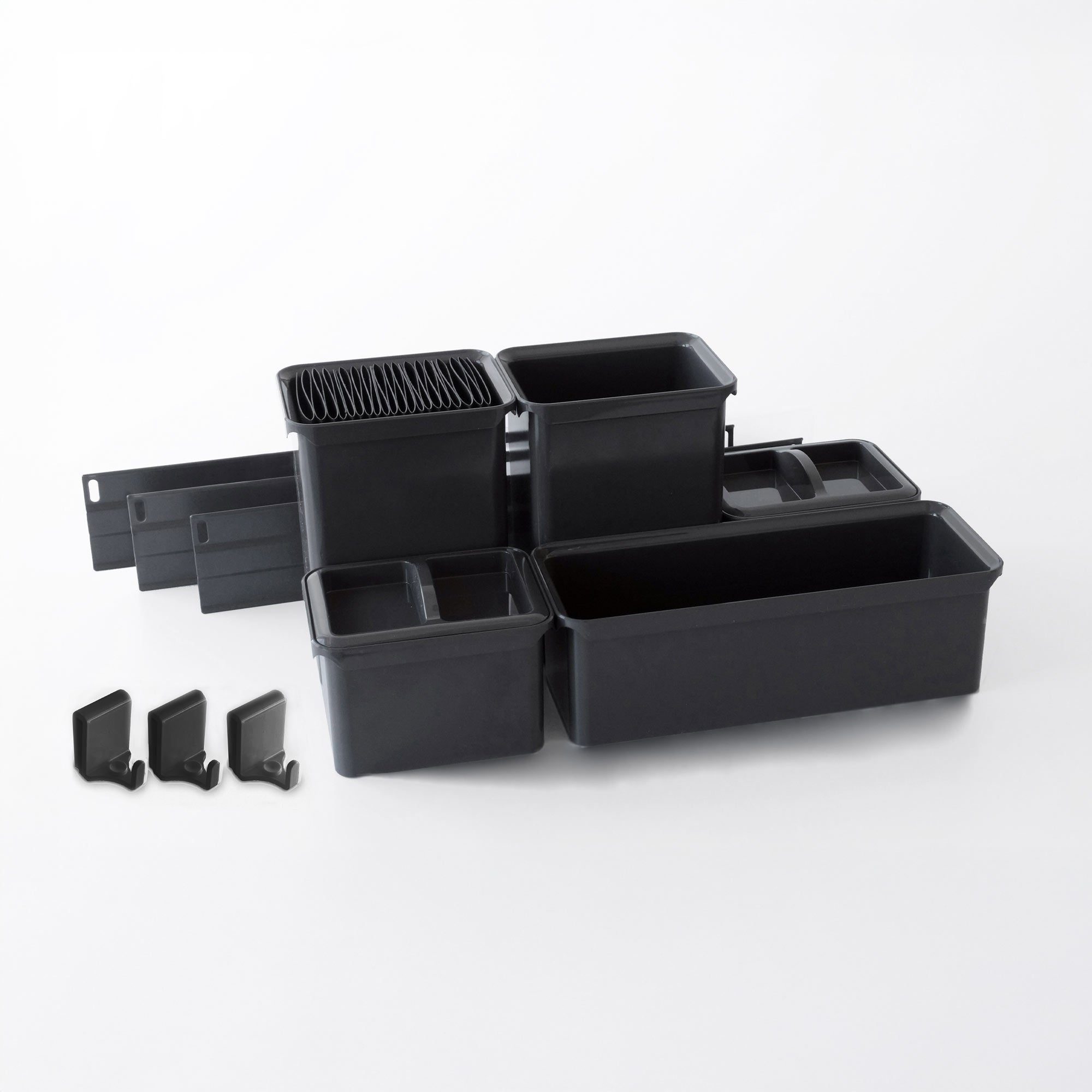 Ein Set YouboXx Einhängeboxen Set 5 aus schwarzem Kunststoff für DISPENSA Apothekerschrank mit Unterteilungen und Clips, angeordnet auf einer weißen Fläche, bietet flexible Organisation in verschiedenen Größen und Formen.