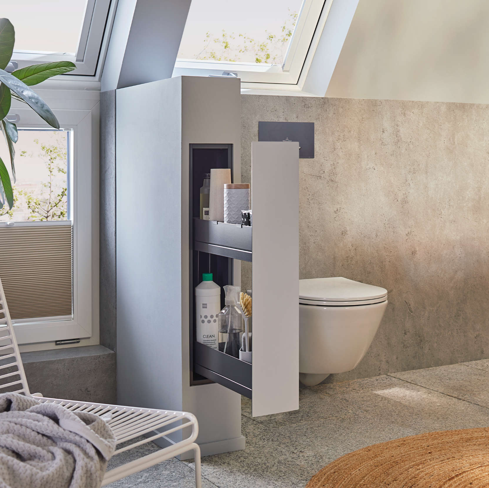 Ein modernes Badezimmer mit einer schwimmenden Toilette und einem hohen, schmalen Ausziehschrank für Toilettenartikel. Der Raum verfügt über ein großes Fenster, strukturierte Wände, einen Stuhl mit Handtüchern und einen runden Teppich auf dem Boden.