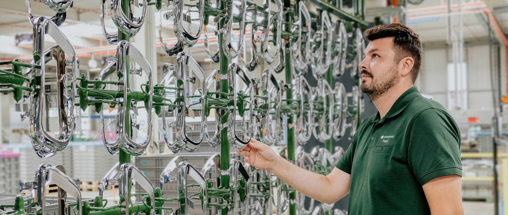 Arbeiter in Produktionshalle prüft bzw. kontrolliert produzierte Artikel.