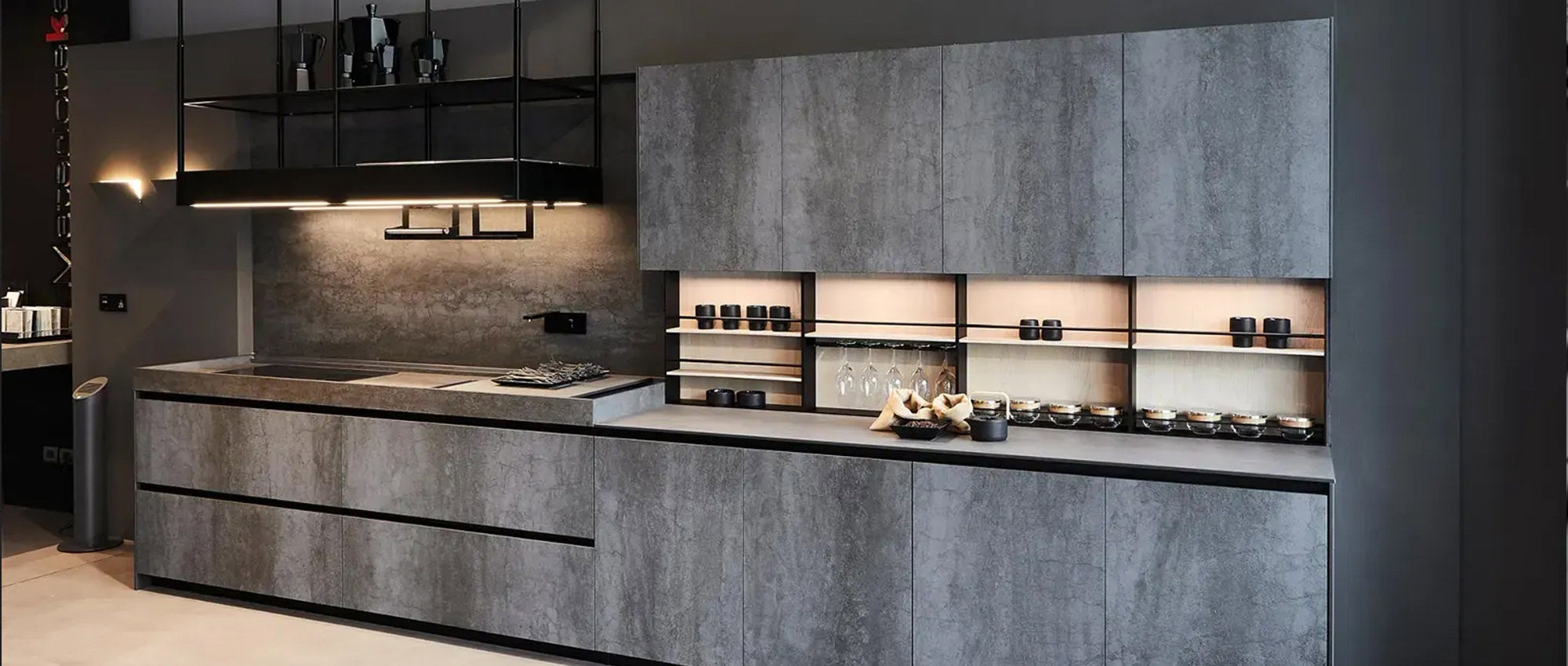 Moderne Küche mit schlichten grauen Schränken, offenen Regalen mit Gläsern und Gläsern, Unterschrankbeleuchtung und einer minimalistischen schwarzen Dunstabzugshaube. Das Design zeichnet sich durch klare Linien und eine zeitgenössische Ästhetik aus.