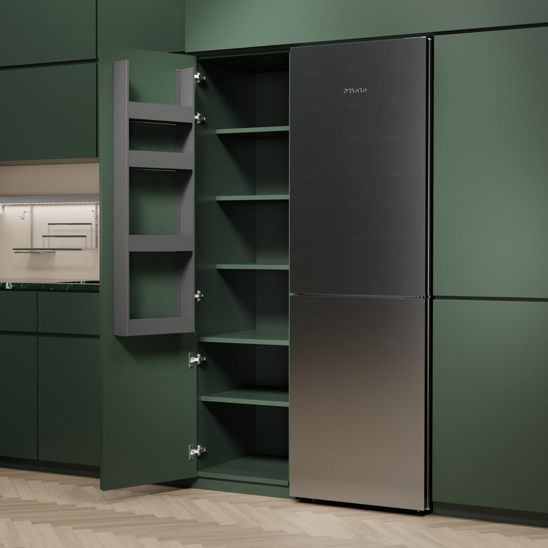Eine moderne Küche mit mattgrünen Schränken, einer offenen, hohen Speisekammer mit seitlichen EasyRack-Regalen von K-Line, einem geschlossenen Miele-Edelstahlkühlschrank und einem hellen Fischgrätboden.