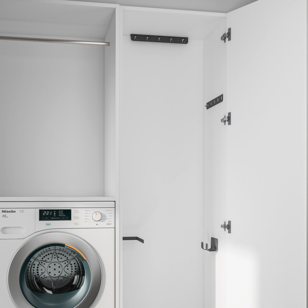 Ein weißer Wäscheschrank mit offener Tür zeigt eine Frontlader-Waschmaschine und eine K-Line Side Hakenleiste - Deckenbefestigung mit mehreren schwarzen Haken und Bügeln zum platzsparenden Aufhängen und Organisieren von Reinigungsmitteln.
