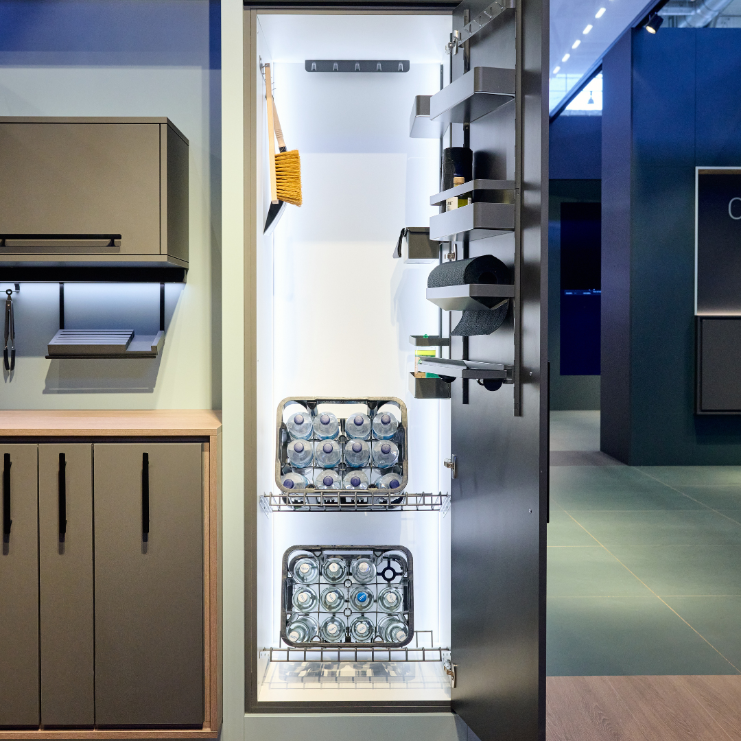 Das Ablage-Set für Getränkekisten - 600 mm sorgt platzsparend für Ordnung: Im modernen, dunklen Küchenschrank werden Reinigungsmittel, Flaschen und Kehrset übersichtlich auf stabilen Ablagen verstaut.