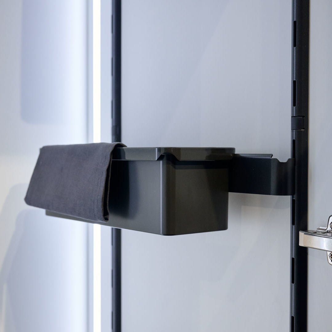 Eine schwarze K-Line Seitenträgerleiste mit Box wird an der Wand montiert, wobei ein schwarzes Tuch an der Seite drapiert und an einer glatten hellgrauen vertikalen Fläche befestigt wird - ideal für Schrank Ordnung.