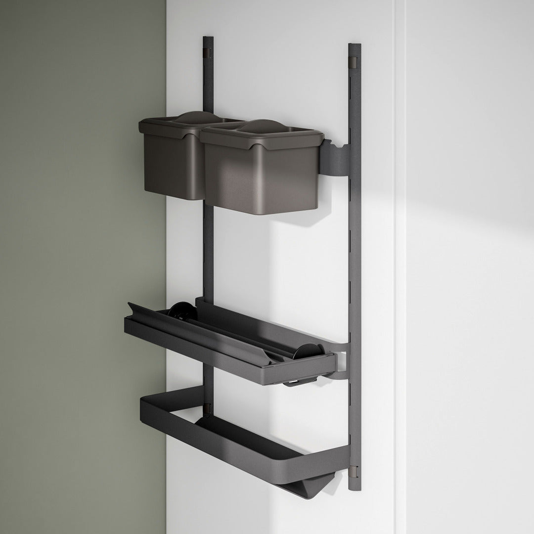 Die K-Line Seite ROLLINERO - Rollenablage ist ein an der Wand montierter schwarzer Metallorganisator mit zwei grauen Behältern und zwei Einlegeböden, ideal für die Aufbewahrung von Artikeln wie Frischhaltefolie oder Alufolie, abgebildet an einer weißen Wand neben einer grünen Akzentwand.
