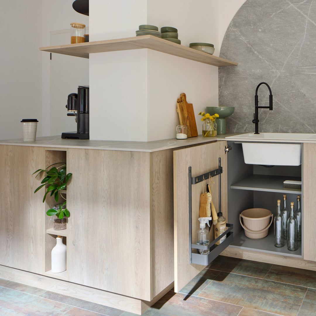 Moderne Küche mit hellen Holzschränken, offenen Regalen und einer eingebauten Pflanzenecke. Unter der Spüle sind die Reinigungsmittel in einem modularen Ordnungssystem organisiert. An der Wand hängt eine K-Line seitliche Hakenleiste - 5 Haken für einfachen Zugriff auf Utensilien.