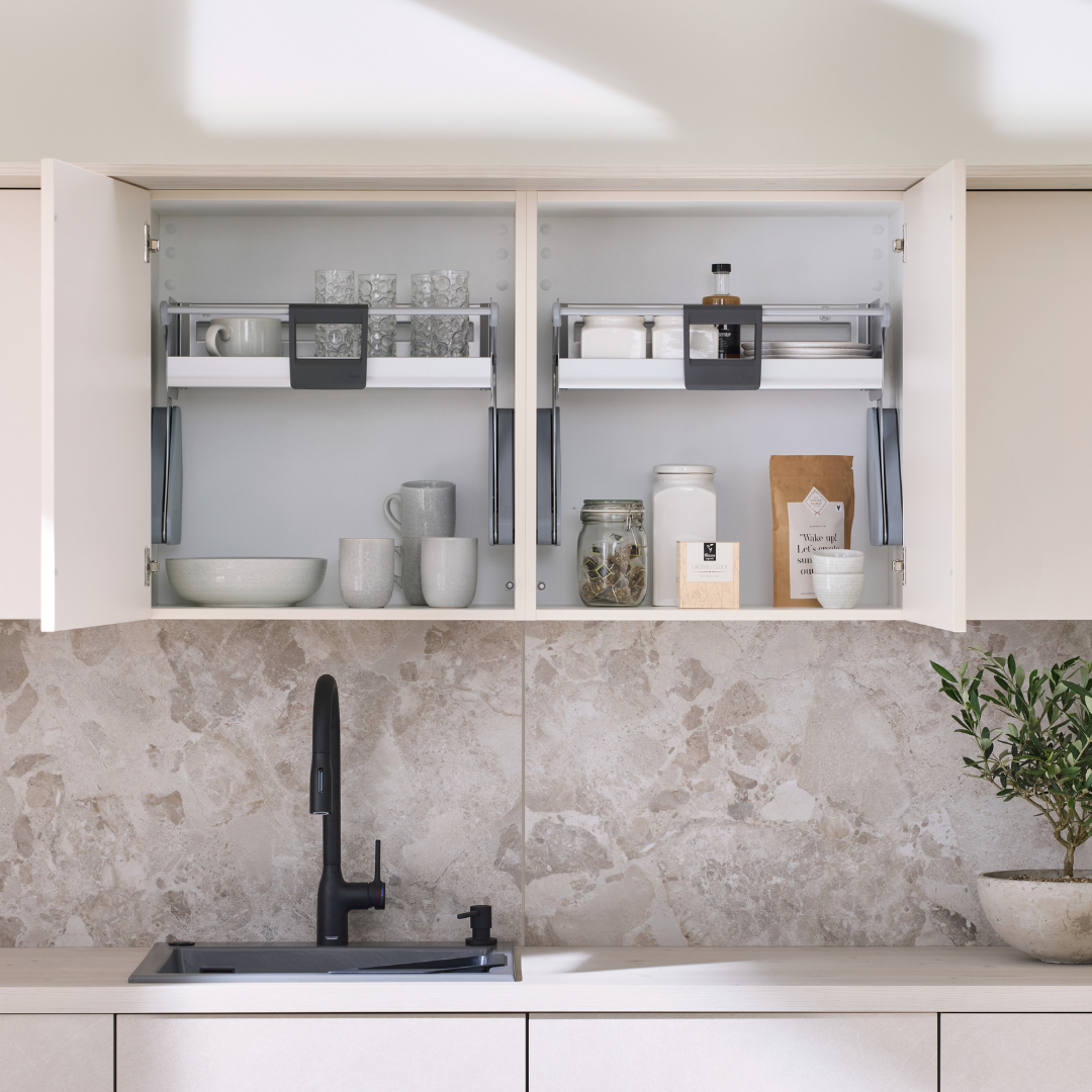 Das iMove 60er single Auszugsystem für den Hängeschrank hält Geschirr, Gläser, Gläser und Behälter ordentlich auf zwei Ebenen über eine Marmor-Rückwand mit schwarzer Armatur und kleiner Pflanze am Waschbecken organisiert.